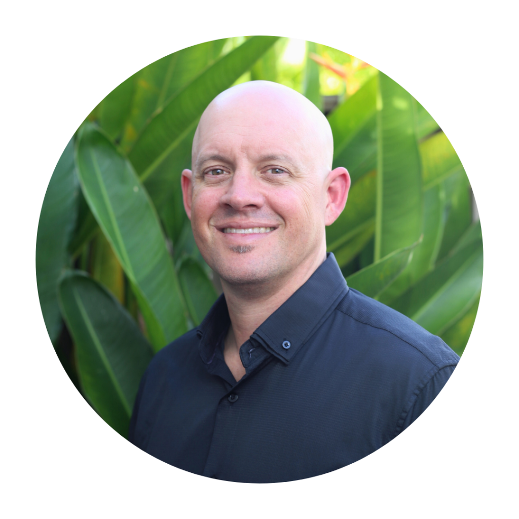 a man smiling in front of leaves